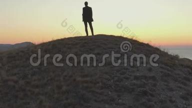 一个穿西装的人站在山顶上，望着海面上的黎明